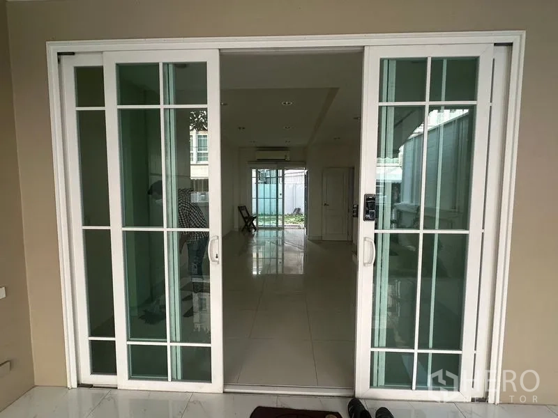 Home Office for rent in Bang Na, Bangkok - White framed sliding glass entry doors opening to a long tiled hallway.