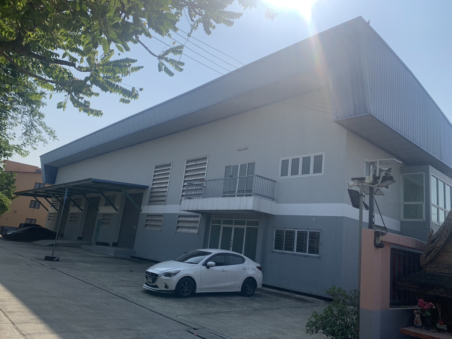 Warehouse for rent in Lam Luk Ka, Pathum Thani - Warehouse exterior with loading bays, metal cladding and on-site parking.