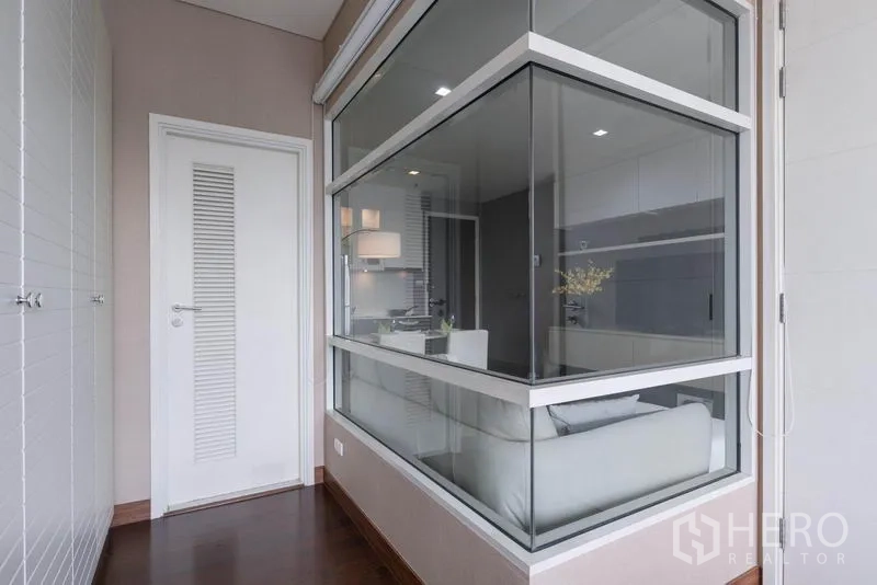 Condominium for rent in Watthana, Bangkok - Hallway with glass partition overlooking the living area and white storage closets.