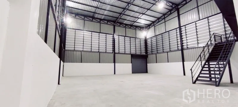 Warehouse for rent in Lam Luk Ka, Pathum Thani - Wide warehouse interior showing louvered ventilation, roller shutter and stairs.