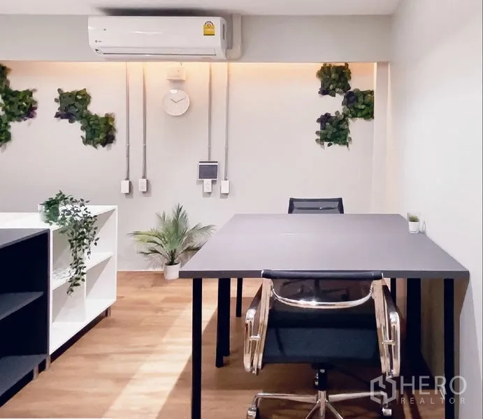 Office Space for rent in Bang Rak, Bangkok - Focused desk area with a black table, task chairs, wall AC, and potted plants.