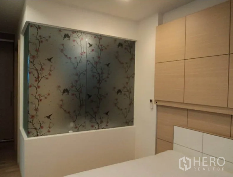 Condominium for rent in Khlong Toei, Bangkok - Bedroom feature wall with frosted glass panel decorated with birds and blossoms.