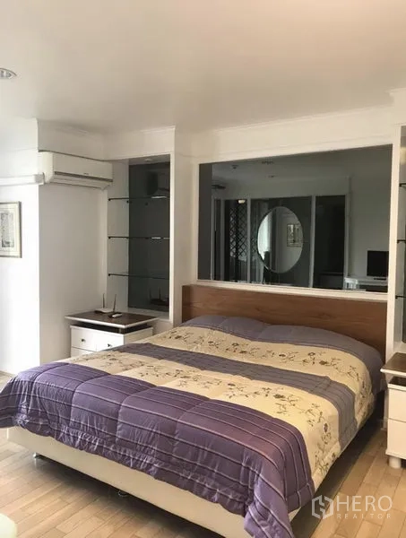 Condominium for rent in Khlong Toei, Bangkok - Cozy bedroom with queen bed, built-in mirrored shelves, air conditioning and wood flooring.