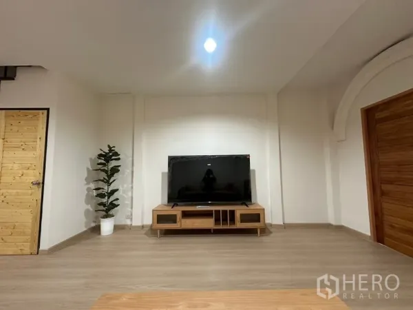 Townhouse for rent or sale in Phra Khanong, Bangkok - Minimal TV wall with large screen, console and indoor plant.