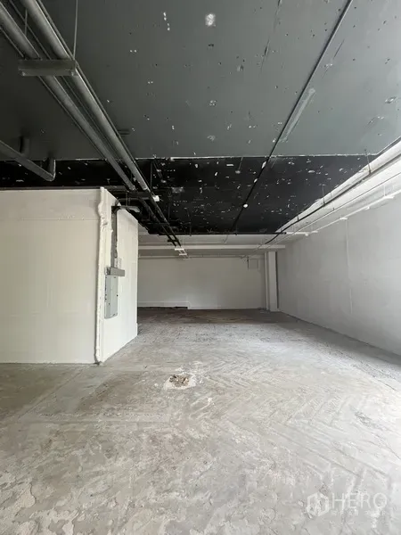 Retail Space for rent - Bare-shell retail unit with exposed black ceiling, concrete floor, and white walls ready for tenant fit-out.