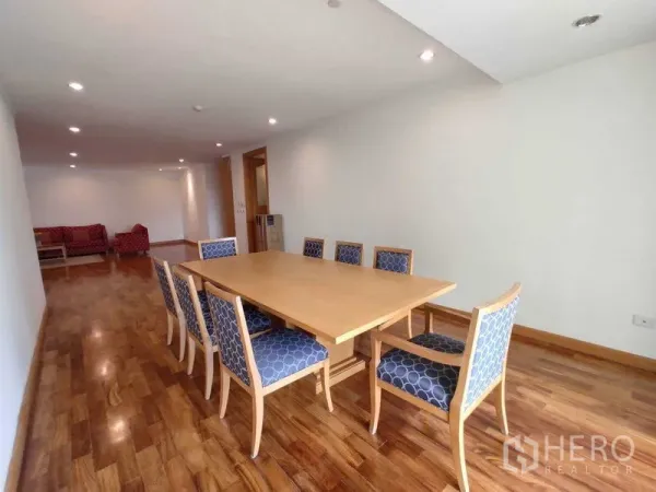 Condominium for rent in Khlong Toei, Bangkok - Spacious dining area with an eight‑seat wooden table and upholstered chairs on hardwood floors.