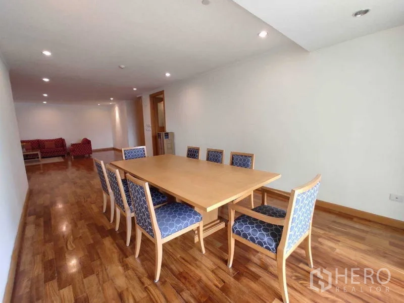 Condominium for rent in Khlong Toei, Bangkok - Spacious dining area with an eight‑seat wooden table and upholstered chairs on hardwood floors.