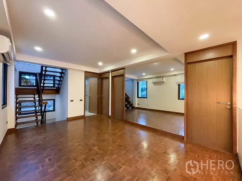 联排别墅 出租在Khlong Toei, Bangkok - 楼上多功能房，整面镜墙、木地板与楼梯相连。