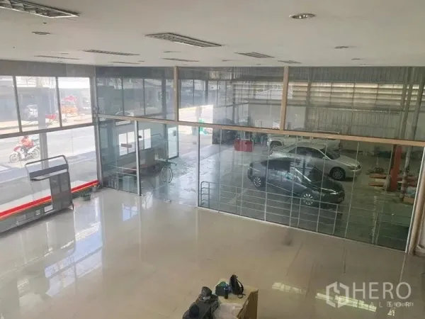 Warehouse for rent in Bang Khen, Bangkok - View from the mezzanine over a bright lobby and glass wall to the workshop with clear street visibility.