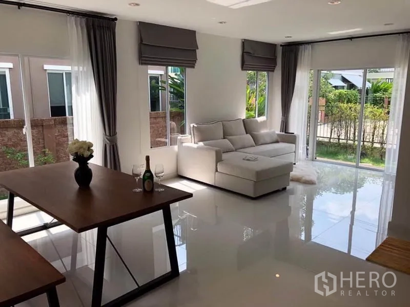 Detached House for rent in Suan Luang, Bangkok - Open-plan living and dining area with large corner windows and glossy floors.
