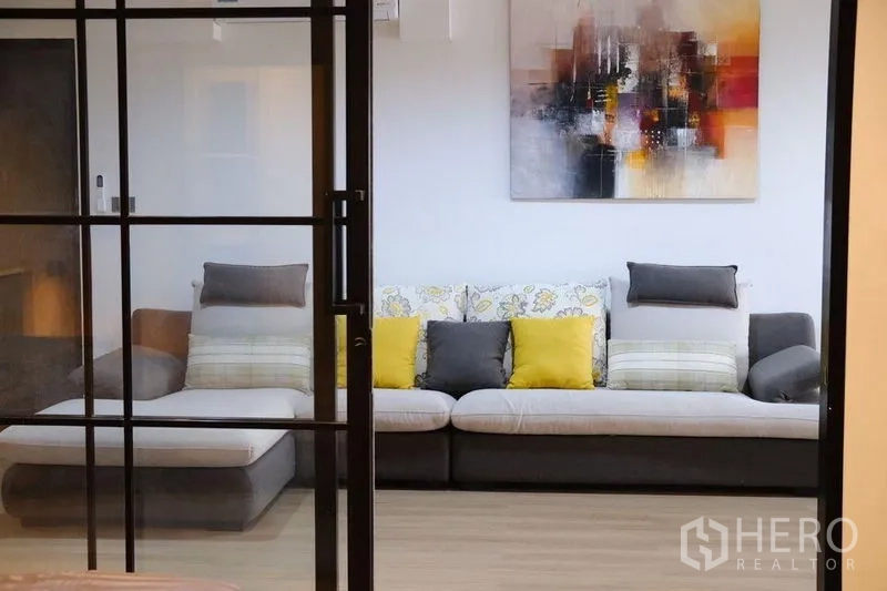 Condominium for rent in Bang Rak, Bangkok - Living room seen through black-framed sliding glass doors.