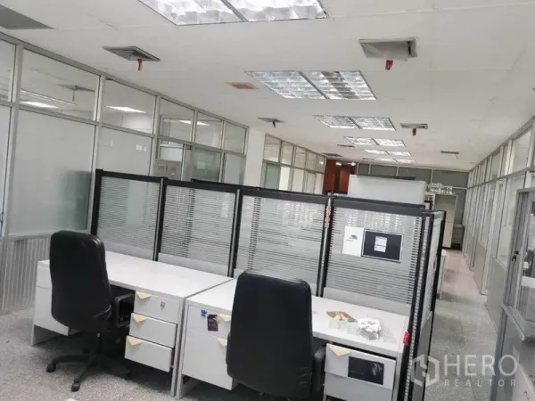 办公空间 出租在Bang Na, Bangkok - 设有隔断屏风与转椅的工位区，顶置荧光灯，玻璃隔间布局。