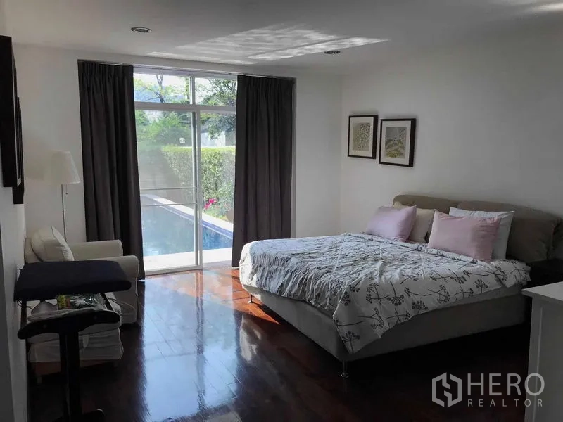 Detached House for sale in Wang Thonglang, Bangkok - Bedroom with glass door to pool terrace, wood floors and seating area