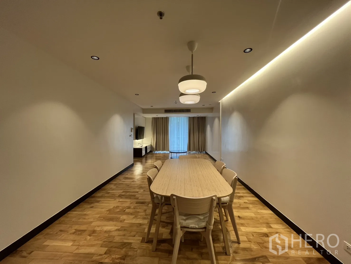 อพาร์ทเมนท์ for rent in Watthana, Bangkok - ห้องนั่งเล่นและรับประทานอาหารแบบโอเพนแปลน พื้นไม้ โคมแขวน โต๊ะยาว มาพร้อมตู้ทีวีและประตูกระจกบานเลื่อนพร้อมผ้าม่าน