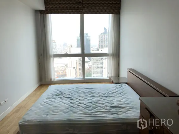 Condominium for rent or sale in Khlong Toei, Bangkok - Bright bedroom with floor-to-ceiling window and expansive Bangkok skyline view.