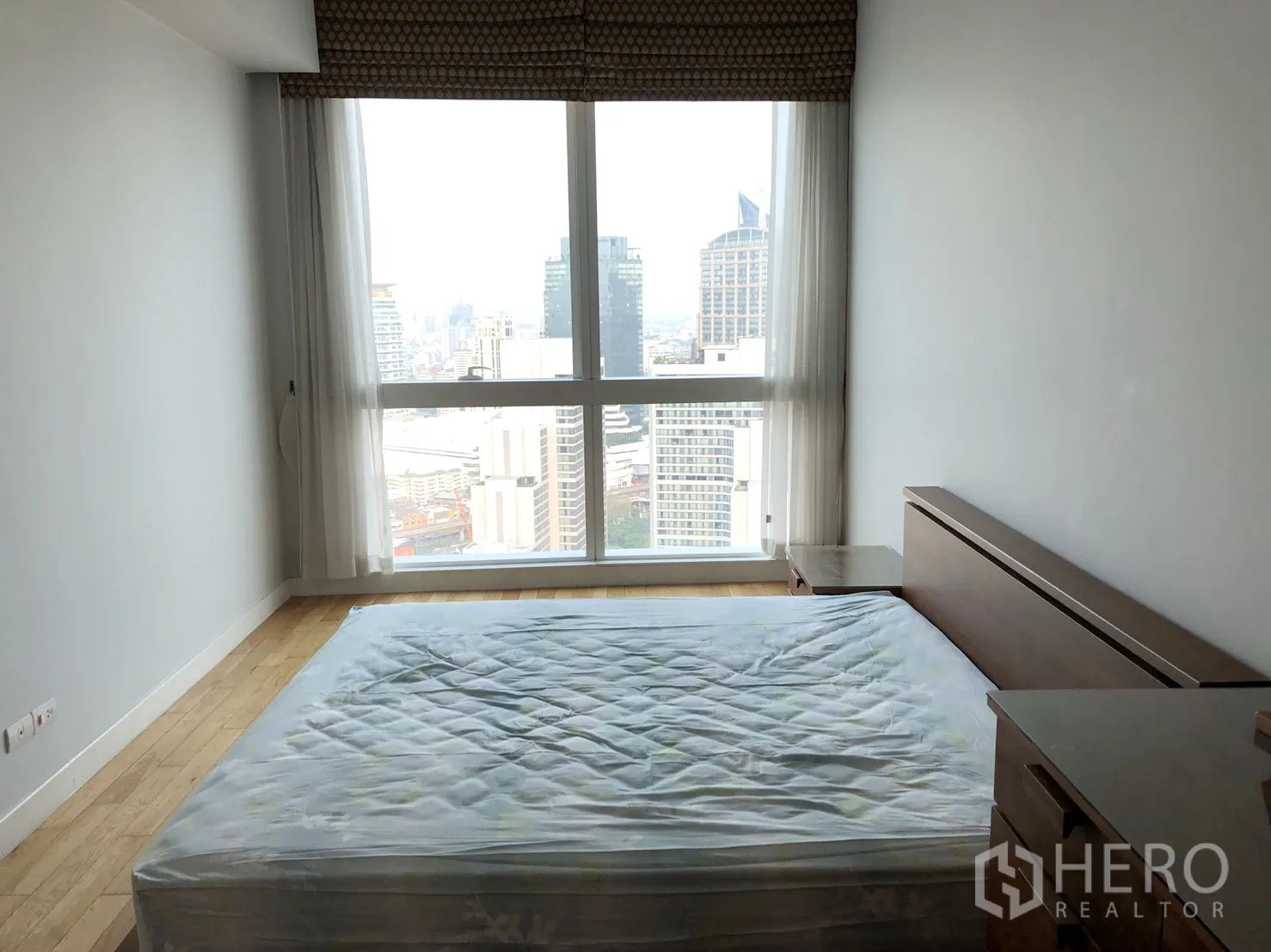 Condominium for rent or sale in Khlong Toei, Bangkok - Bright bedroom with floor-to-ceiling window and expansive Bangkok skyline view.