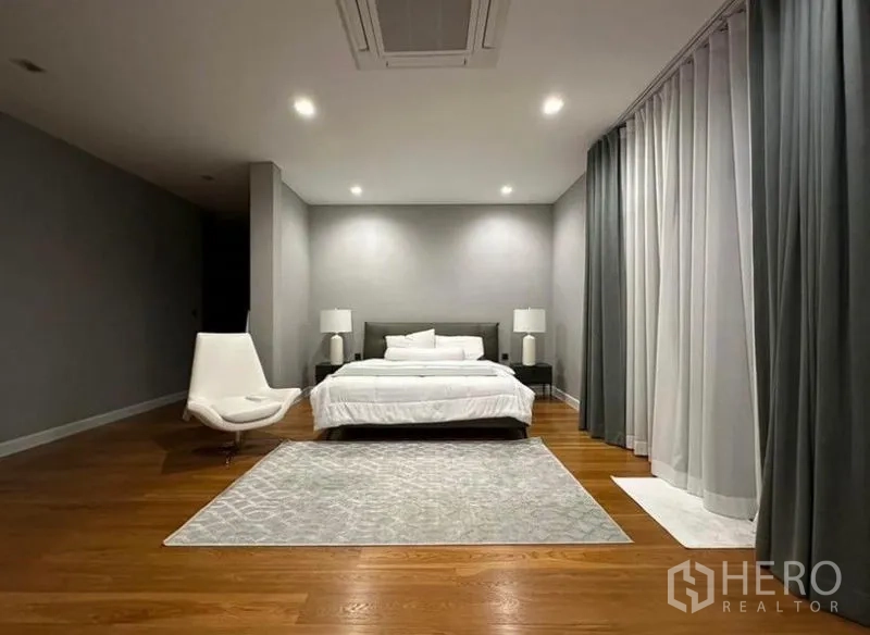 Detached House for rent - Spacious minimalist master bedroom with wood flooring, large rug and full‑height curtains.