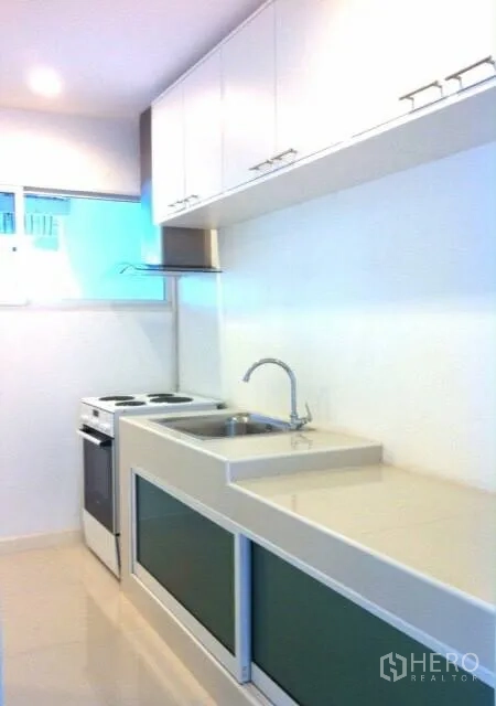 Townhouse for rent or sale in Suan Luang, Bangkok - Fitted kitchen with long countertop, sink and electric stove.