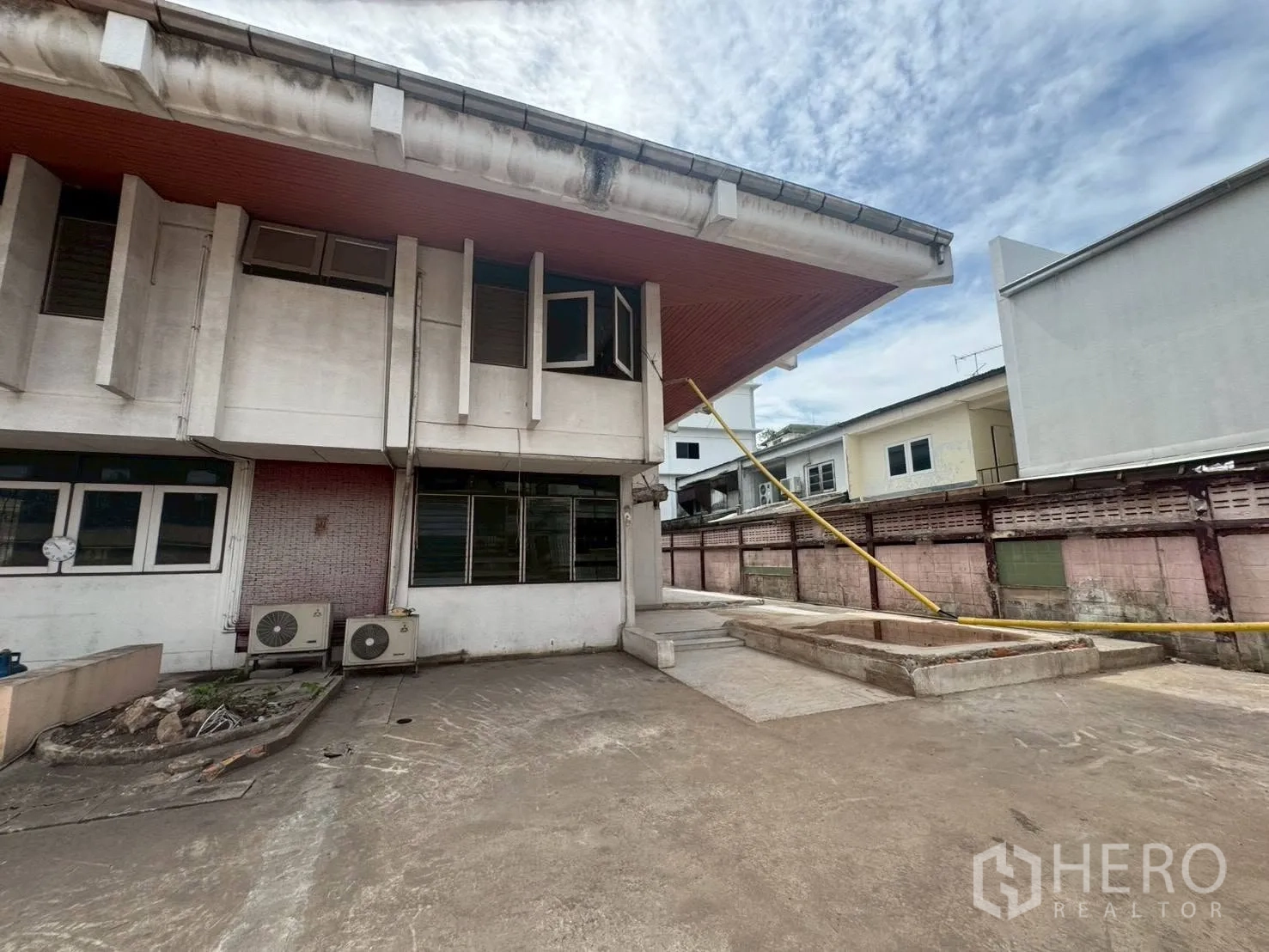 Detached House for rent or sale in Watthana, Bangkok - Rear exterior with wide paved area, AC compressor units, and overhanging roof.