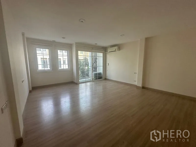 Home Office for rent in Bang Na, Bangkok - Large empty multipurpose room with wooden floors, balcony access and air conditioning.