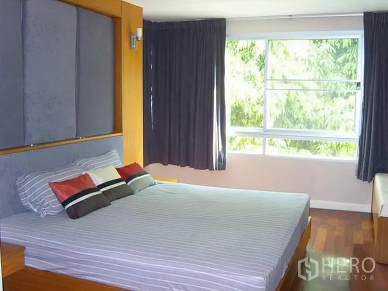 Condominium for rent in Watthana, Bangkok - Bedroom with padded headboard, hardwood floors and wide windows.