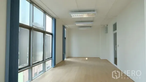 Office Space for rent in Bang Rak, Bangkok - Bright 50 sqm office room with large windows, vertical blinds, light wood floors and white walls.