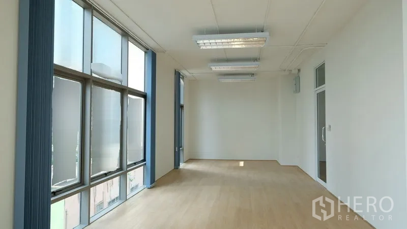 Office Space for rent in Bang Rak, Bangkok - Bright 50 sqm office room with large windows, vertical blinds, light wood floors and white walls.