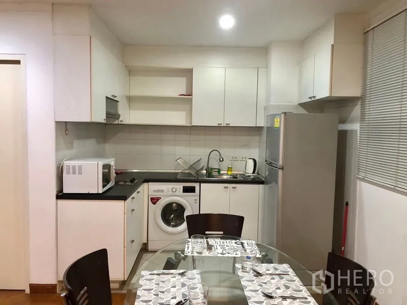公寓 出租或出售在Watthana, Bangkok - 紧凑厨房，白色橱柜、冰箱、微波炉、水槽和洗衣机，邻近餐桌