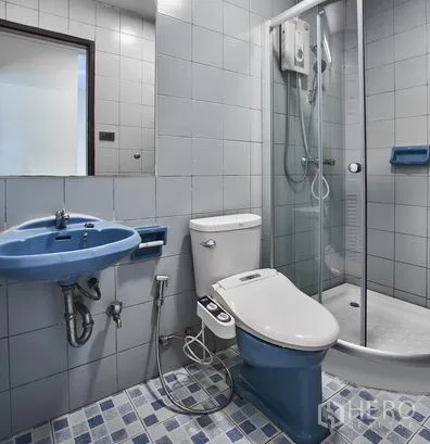 Condominium for rent in Watthana, Bangkok - Compact bathroom with glass shower enclosure, bidet hose and blue sink.