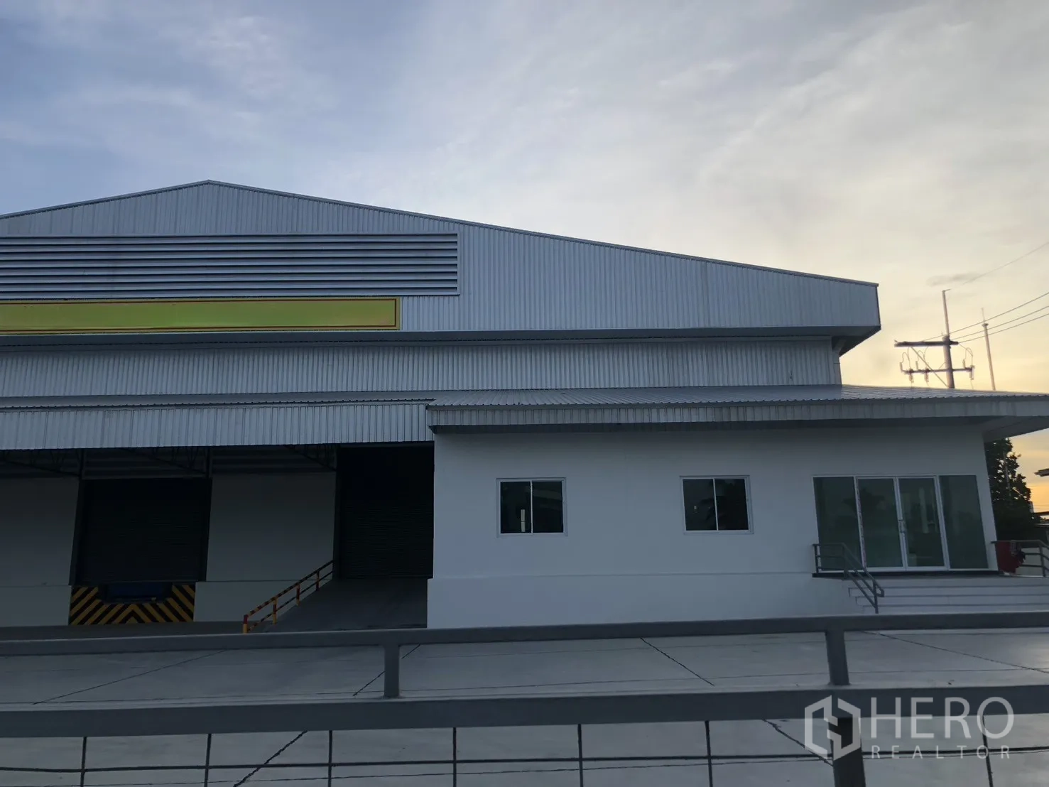 工厂 for rent in Si Racha, Chon Buri - 现代厂房外立面，卷帘门与前方大片硬化地面。