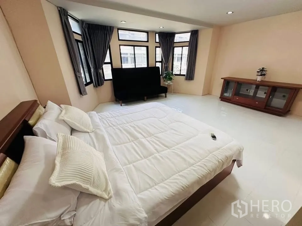 Townhouse for rent - Spacious bedroom with a king bed, sofa, bay-style windows, and a low cabinet.