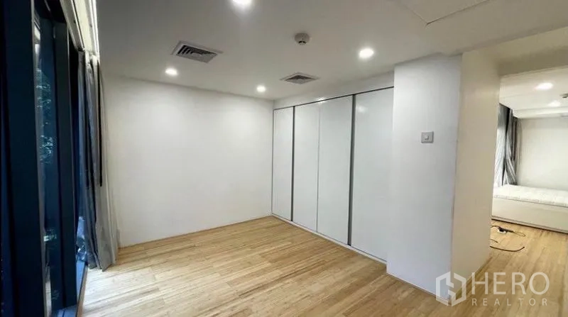 公寓 出租在Watthana, Bangkok - 明亮卧室，整面白色衣柜与大窗，木地板