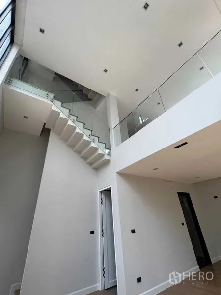 带办公室的家 出售在Wang Thonglang, Bangkok - 室内高挑通透，玻璃栏板楼梯与开放式空间。