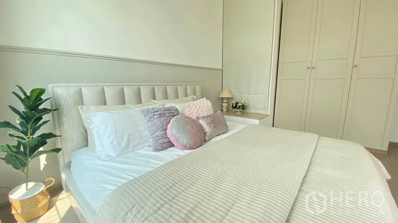 Townhouse for rent in Prawet, Bangkok - Master bedroom detail with upholstered headboard, built-in wardrobes and bedside decor.