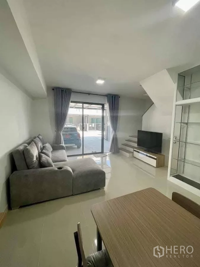 联排别墅 出租在Bang Phli, Samut Prakan - 开放式起居区，推拉门通向车棚，电视柜与楼梯