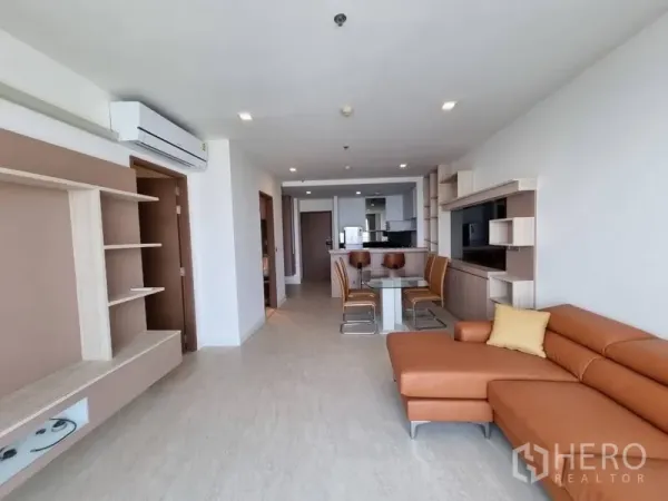 公寓 出租在Watthana, Bangkok - 开放式起居区，L形皮沙发与壁挂置物架，连接阳台。