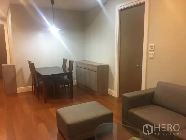 Condominium for rent in Khlong Toei, Bangkok - Dining area with pendant light, four-seat table and wood floors beside an interior doorway.