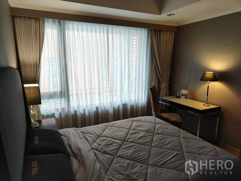 公寓 出租或出售在Pathum Wan, Bangkok - 卧室带临窗书桌，绗缝床品与柔和台灯。