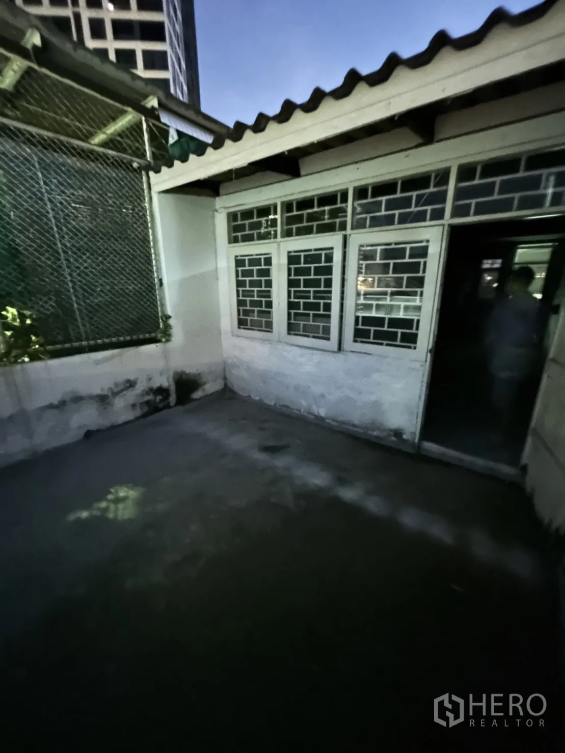 Shophouse for rent in Khlong Toei, Bangkok - Small outdoor terrace with windowed wall and city building backdrop.