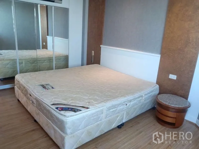 Condominium for rent in Khlong Toei, Bangkok - Bedroom with mirrored wardrobe, upholstered headboard and bedside tables.