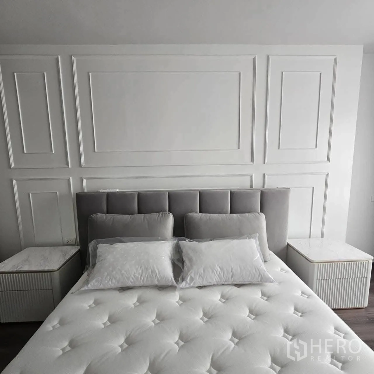 คอนโด for rent in Huai Khwang, Bangkok - ห้องนอนหลักมีหัวเตียงบุผ้า ผนังเซาะร่อง และโต๊ะข้างเตียงเข้าชุด