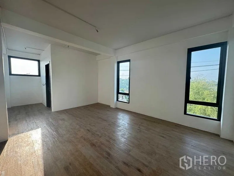Home Office for rent in Don Mueang, Bangkok - Bedroom with wood-look flooring and tall windows on two sides.