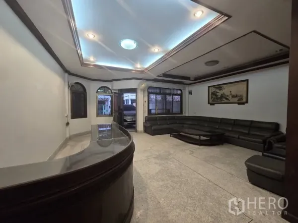 Home Office for rent in Sathon, Bangkok - Spacious living and reception area with L-shaped sofa and coffered ceiling lights.