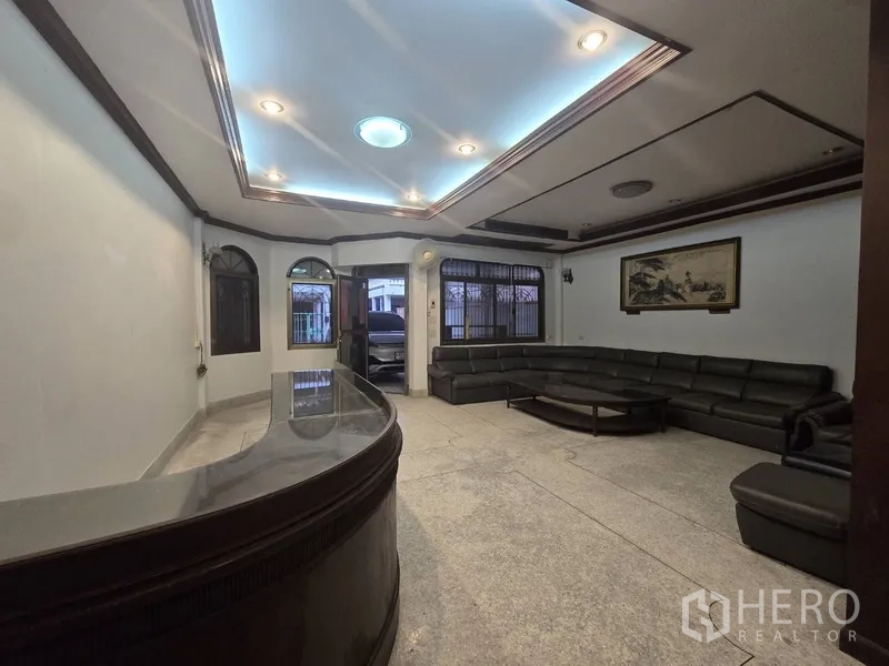 Home Office for rent in Sathon, Bangkok - Spacious living and reception area with L-shaped sofa and coffered ceiling lights.