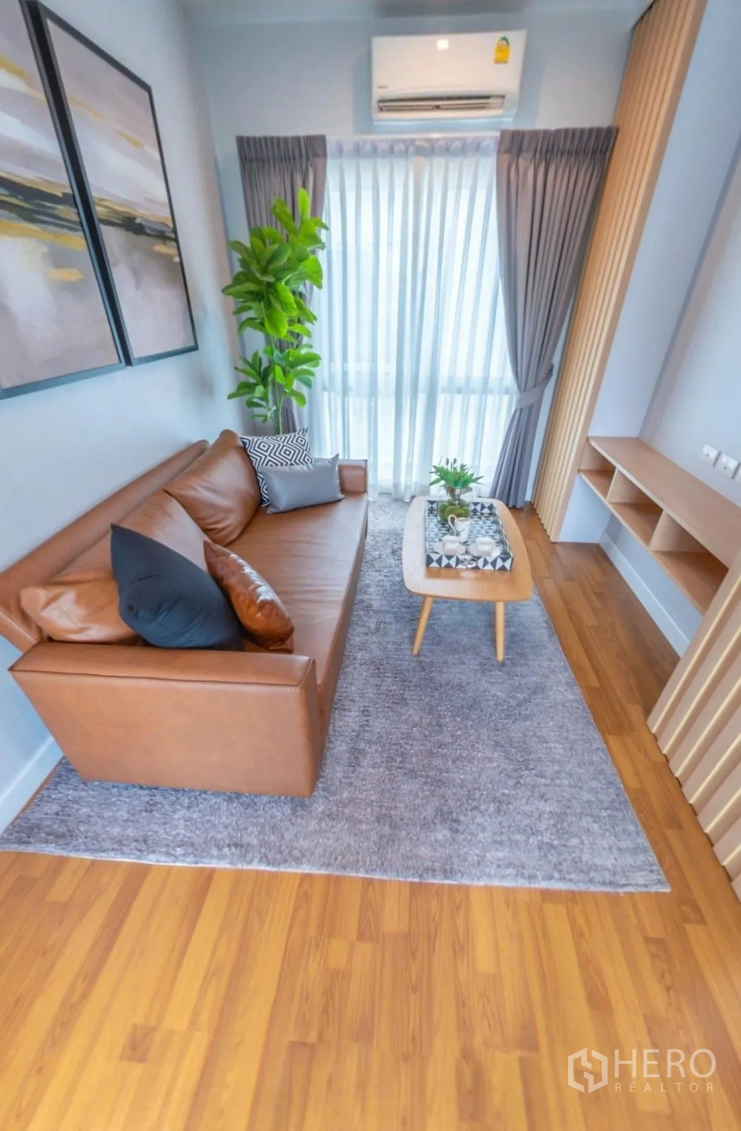 Detached House for rent in Lam Luk Ka, Pathum Thani - Small family lounge with leather sofa, coffee table, tall plant, and sheer curtains.