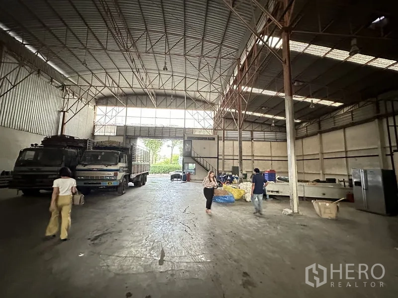 Factory for rent in Bang Bua Thong, Nonthaburi - High-bay loading area with trucks parked and rear access opening.