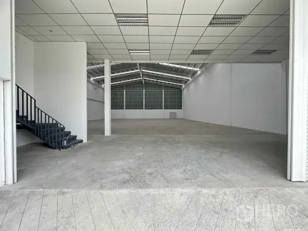 Factory for rent in Khlong Luang, Pathum Thani - Spacious warehouse interior with high ceiling, reinforced concrete floor, and a stair to the mezzanine office.
