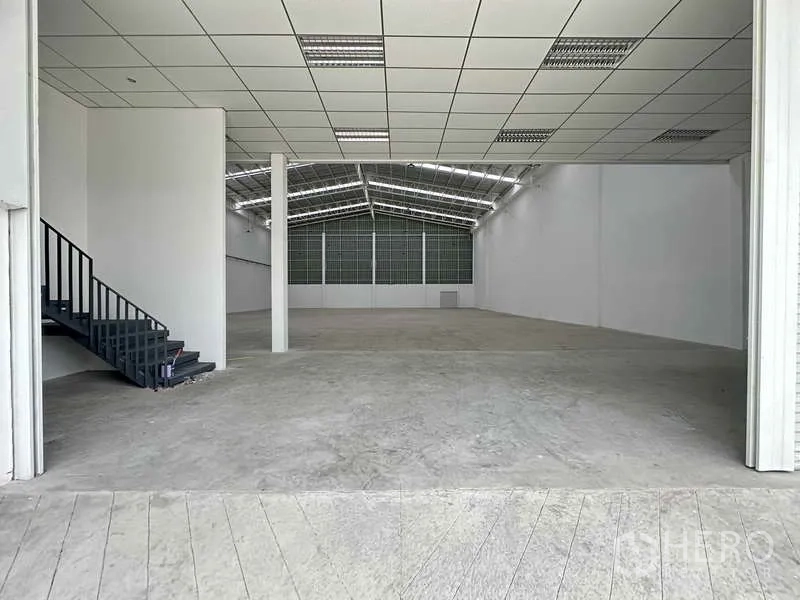 Factory for rent in Khlong Luang, Pathum Thani - Spacious warehouse interior with high ceiling, reinforced concrete floor, and a stair to the mezzanine office.