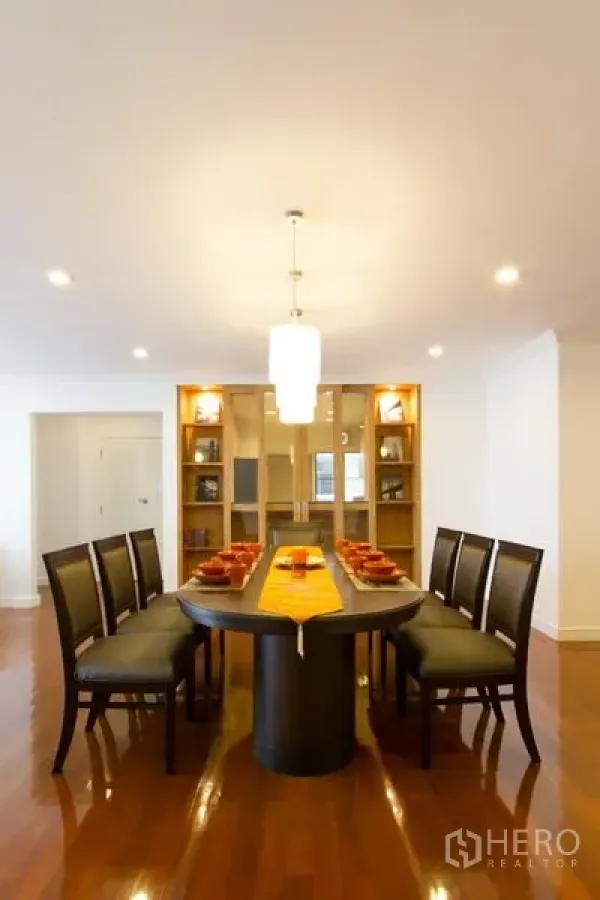 Apartment for rent in Watthana, Bangkok - Formal dining area with an oval table, pendant light and illuminated built-in shelving.