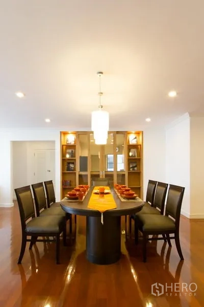 Apartment for rent in Watthana, Bangkok - Formal dining area with an oval table, pendant light and illuminated built-in shelving.